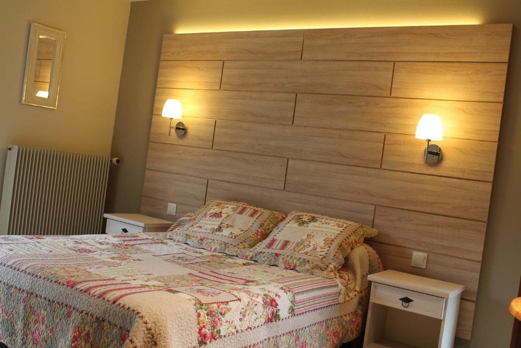 Schlafzimmer mit einem großen Kopfteil aus Holz und einem Bett in der Unterkunft Hôtel Restaurant Aux Genêts d'Or in Mandailles