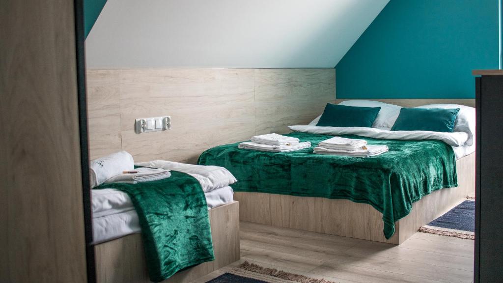 a bedroom with a bed with a green blanket at OSADA Rokicie in Kluszkowce