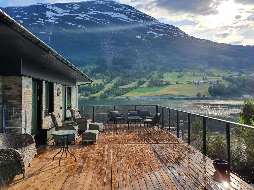 a deck with chairs and tables and a view of a mountain at Olden Panorama Apartments - Fjord view - High Standard in Olden