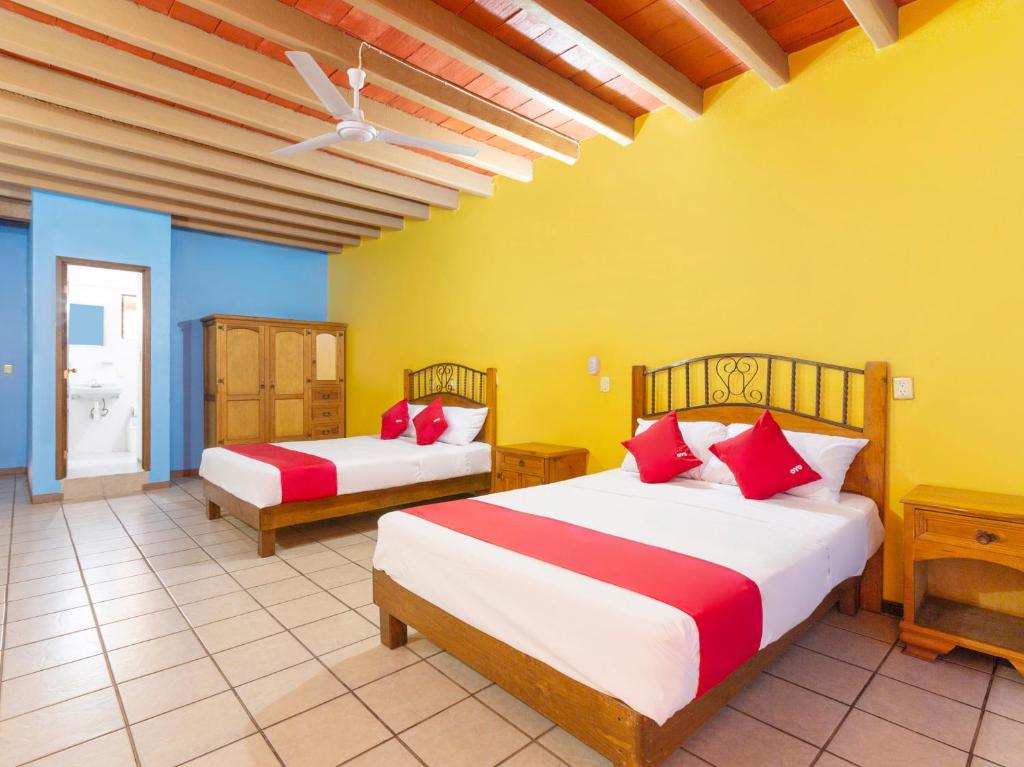 two beds in a room with yellow and blue at Hotel Posada San Rafael in Oaxaca City