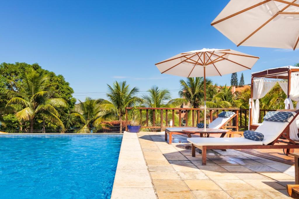uma piscina com cadeiras e guarda-sóis ao lado de um resort em Bahiamarela Boutique Hotel & SPA em Búzios