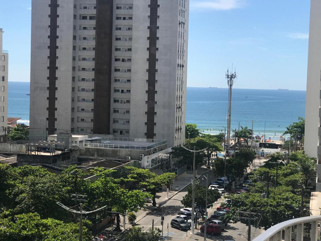 eine Stadtstraße mit einem großen Gebäude und dem Meer in der Unterkunft Cara da Praia in Guarujá