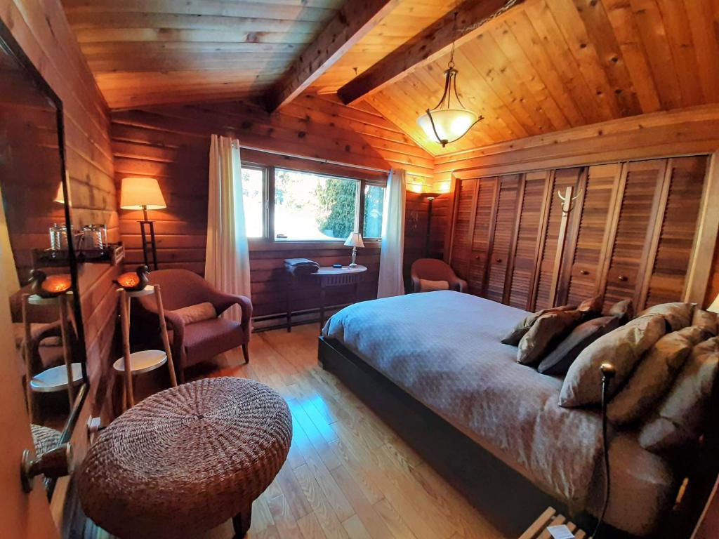 a bedroom with a bed in a wooden room at Gîte le 308 Chambre bord de l'eau oka in Oka