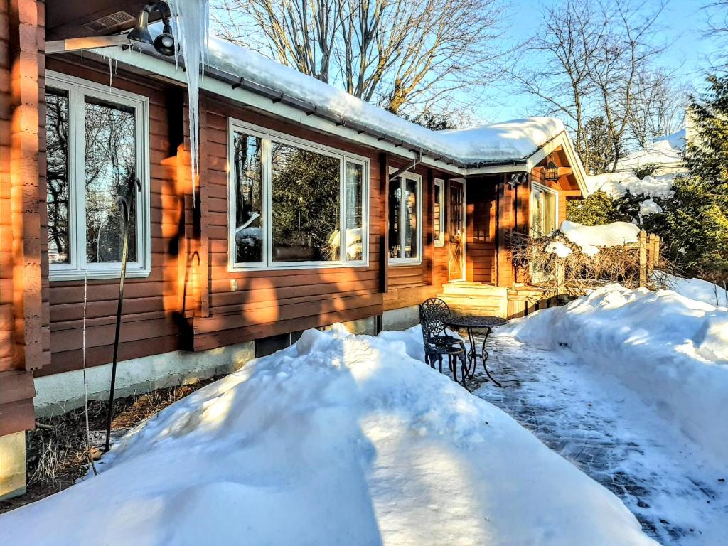 a house with a pile of snow in front of it at Gîte le 308 Chambre bord de l'eau oka in Oka