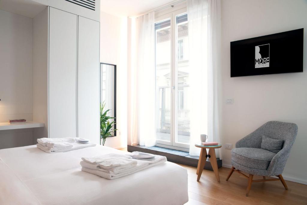 a bedroom with a bed and a chair and a window at BMORE Duomo - Luxury Apartments near Duomo in Milan