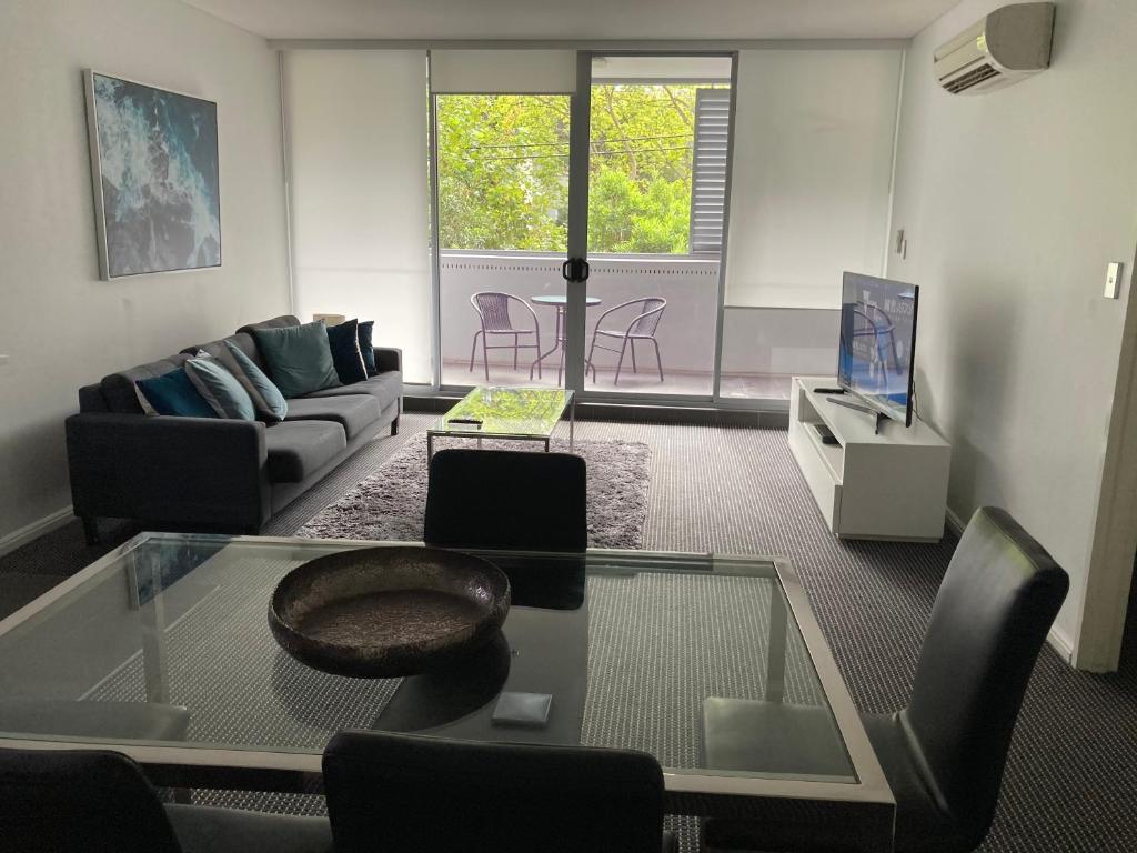 - un salon avec un canapé et une table en verre dans l'établissement North Sydney Wyndel Apartments-MIL1005, à Sydney