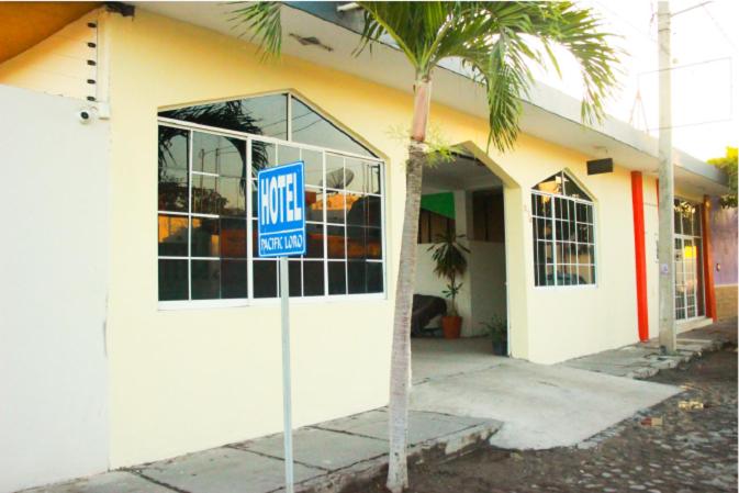 een huurbord voor een gebouw met een palmboom bij Hotel Pacific in Tecomán