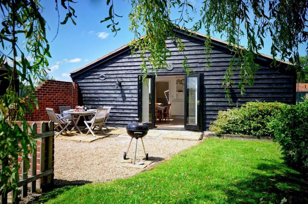a black cottage with a grill in the yard at East Green Farm Cottages - Gardeners Cottage in Saxmundham