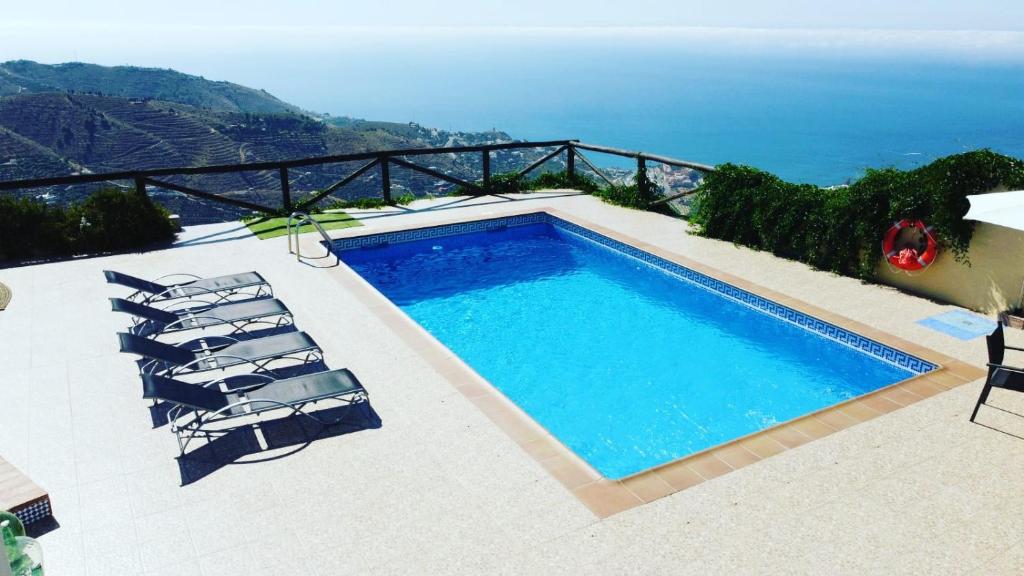 a swimming pool with chairs and the view of the ocean at Cortijo Mirador de Almuñecar in Taramay