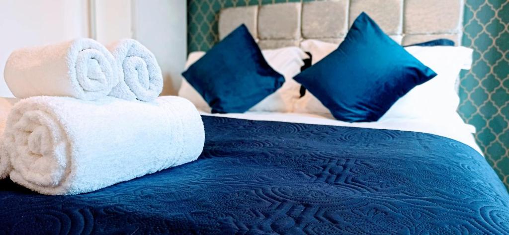 a blue and white bed with towels and pillows at Brookside 2BR Flat Oxford City Centre Free Parking in Oxford