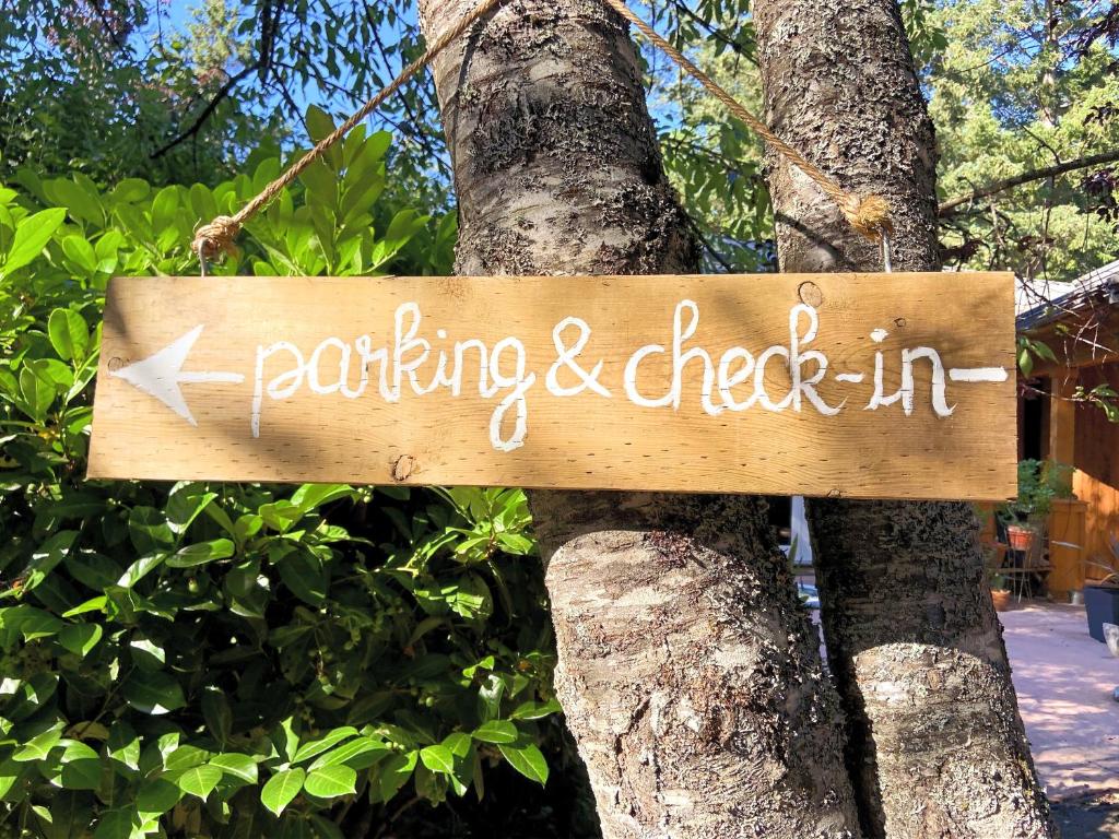 a sign that reads parking and check in hanging on a tree at Wisteria Guest House in Ganges