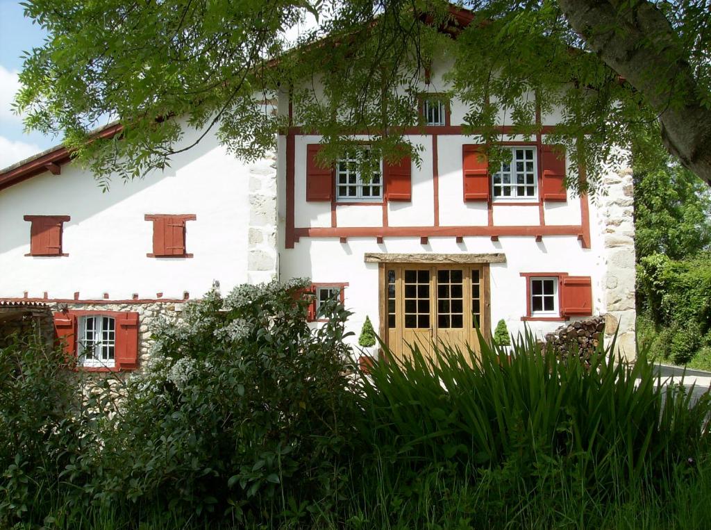 Una casa vieja con persianas rojas. en Maison Anderetea, en Mendionde