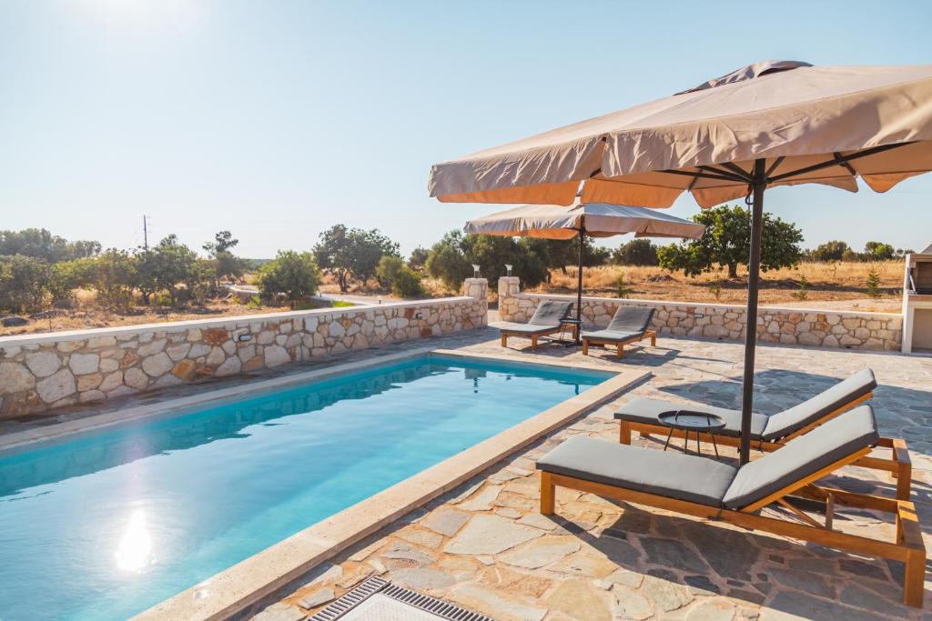 una piscina con due sedie e un ombrellone di Private, Quiet, Isolated Villa in Chania / HomeAlone a Chorafakia