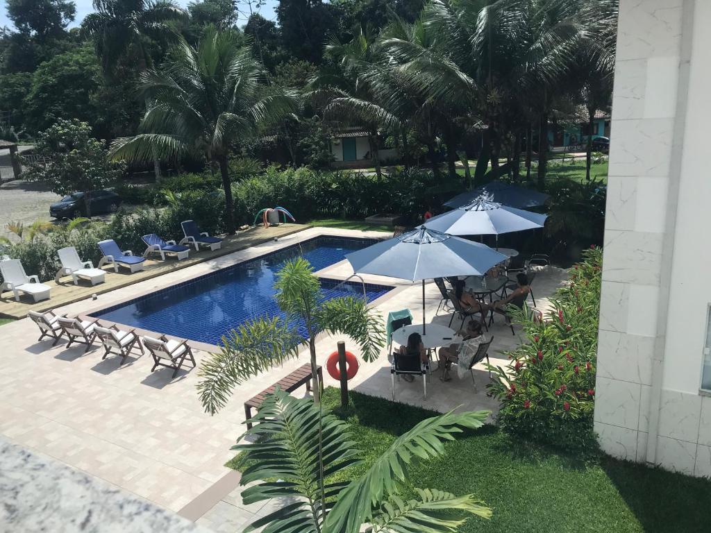 a swimming pool with chairs and umbrellas and a pool at Perequê-Açu Aparts in Paraty