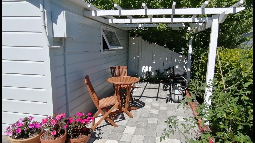 un patio con mesa, sillas y flores en Garden Cottage, en Hastings