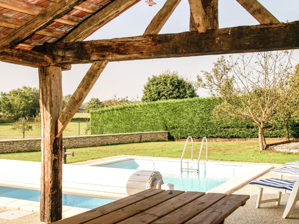 a swimming pool with a wooden pergola and a wooden table at Superb holiday home with pool in Cressensac