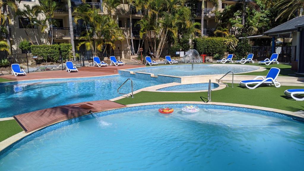a large swimming pool with chairs and a fountain at Mermaid Beach Apartment in Gold Coast