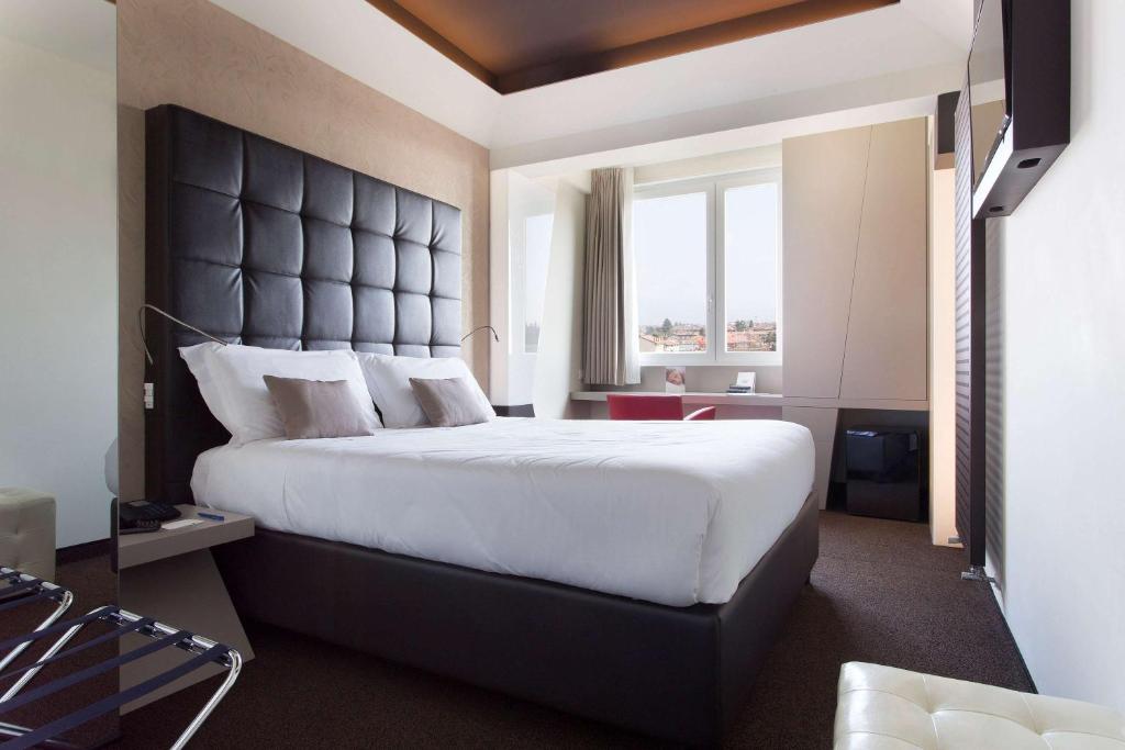 ein Schlafzimmer mit einem großen Bett mit einem großen Kopfteil in der Unterkunft Best Western Hotel Continental in Udine