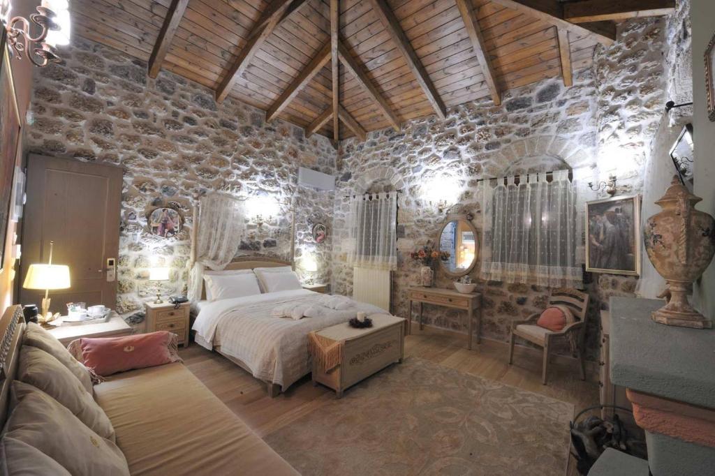 a bedroom with a bed and a stone wall at Armonia Hotel in Kefalari
