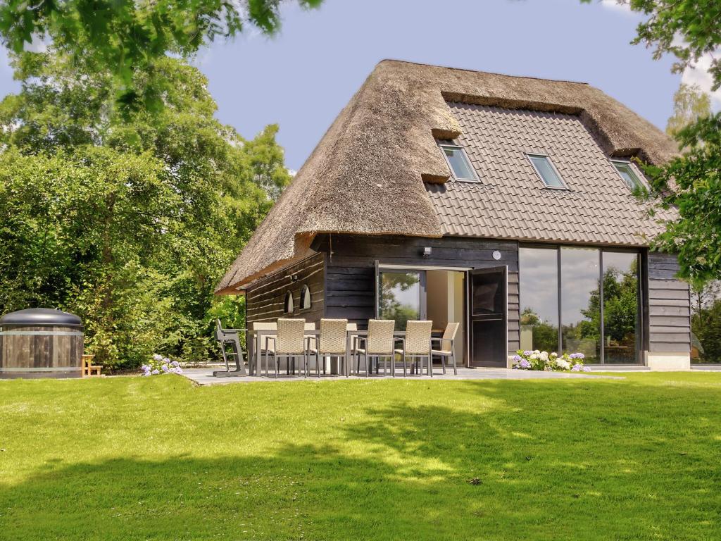 a thatch roof house with chairs and a lawn at Tranquil Farmhouse in Rijsbergen with Hot Tub and Garden in Rijsbergen
