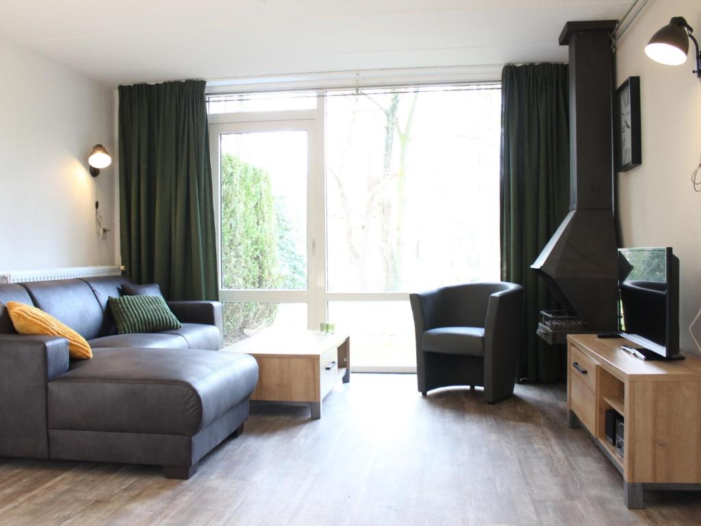 a living room with a couch and a tv at Bungalow with garden, located in a natural area in Vledder