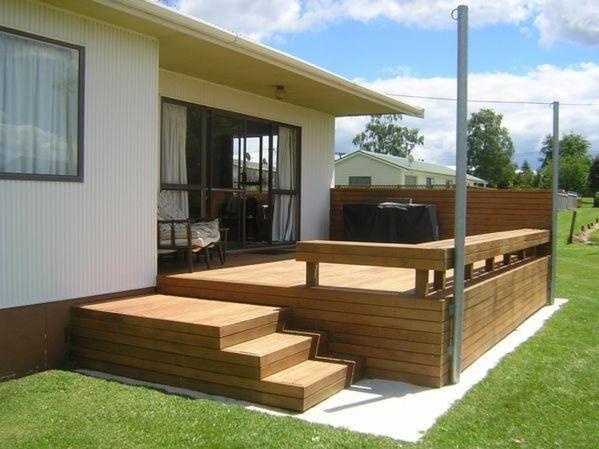 a wooden deck with a bench on the side of a house at The Lakehouse Bach - Lake Rotoiti Bach in Rotoiti