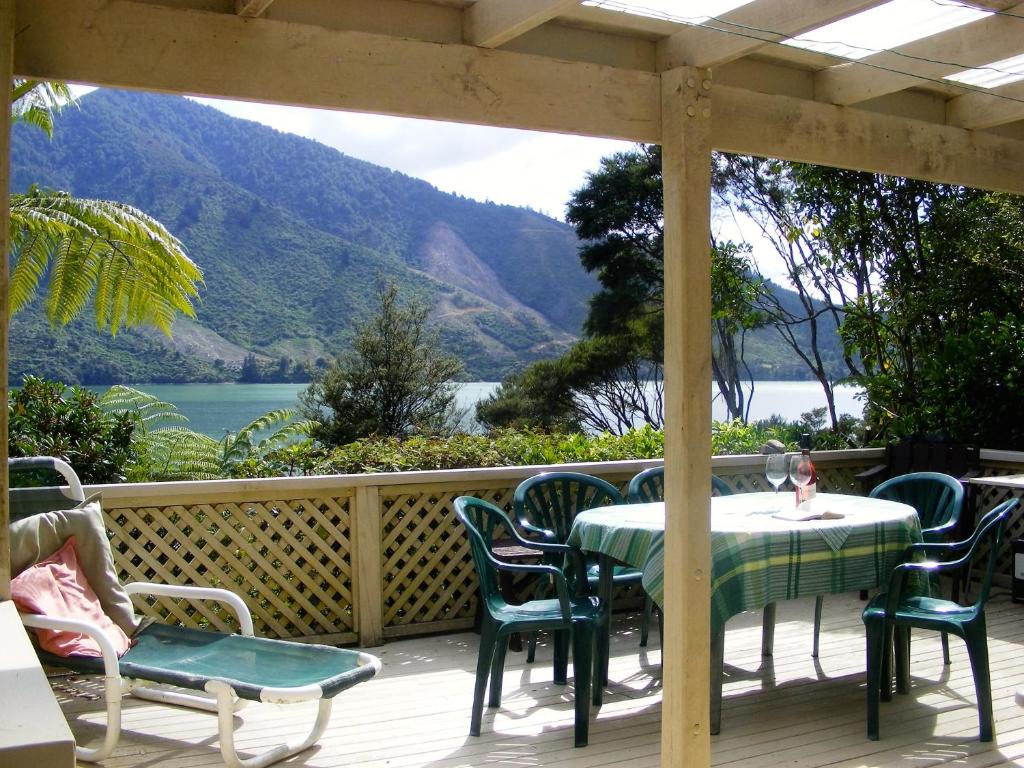 uma mesa e cadeiras num deque com vista para um lago em Fernleigh - Moetapu Bay Holiday Home em Whatanihi