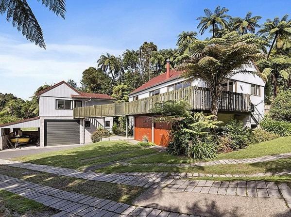 une grande maison blanche avec un palmier devant dans l'établissement Lake House and Studio - Lake Rotoiti Holiday Home, à Okere Falls