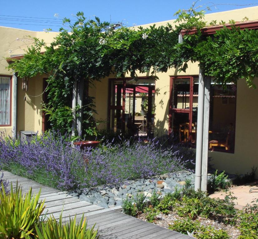 a garden with purple flowers in front of a house at El Kedira - Campbells Beach Holiday Home in Tawharanui