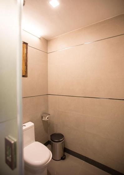 a bathroom with a toilet and a trash can at Dunhill Beach Resort in Agonda