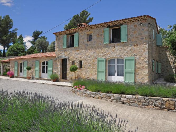 a stone house with green shutters on a street at Provencal air conditioned villa in Fayence