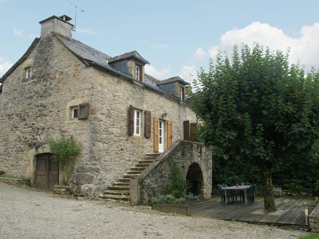 an old stone house with a table in front of it at Cosy holiday home with garden in Saint-Geniez-dʼOlt