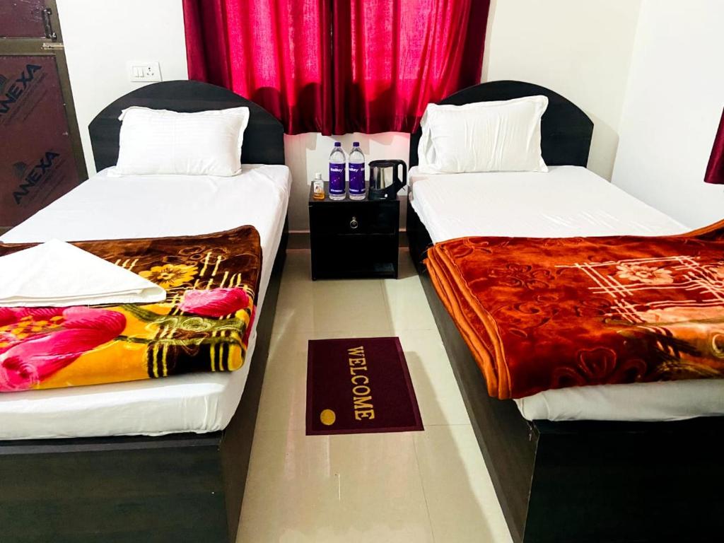 two beds in a room with red curtains at Gaurav guest house in Bodh Gaya