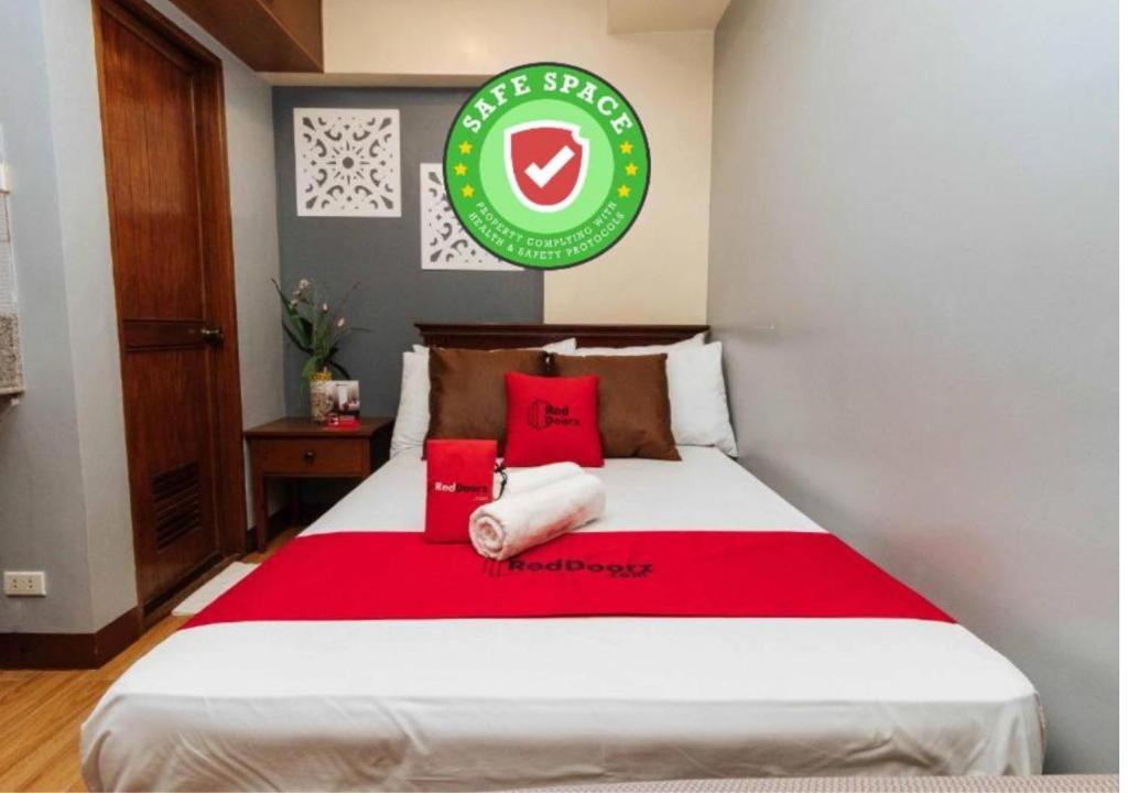 een slaapkamer met een groot bed met rode kussens bij RedDoorz @ Moonwalk Paranaque in Manilla
