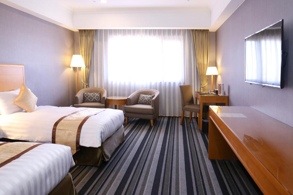 a hotel room with two beds and a window at Fushin Hotel - Tainan in Tainan