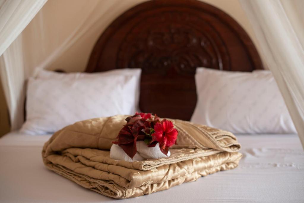a bed with a blanket and a flower on it at Sea View Beach Hotel in Zanzibar City