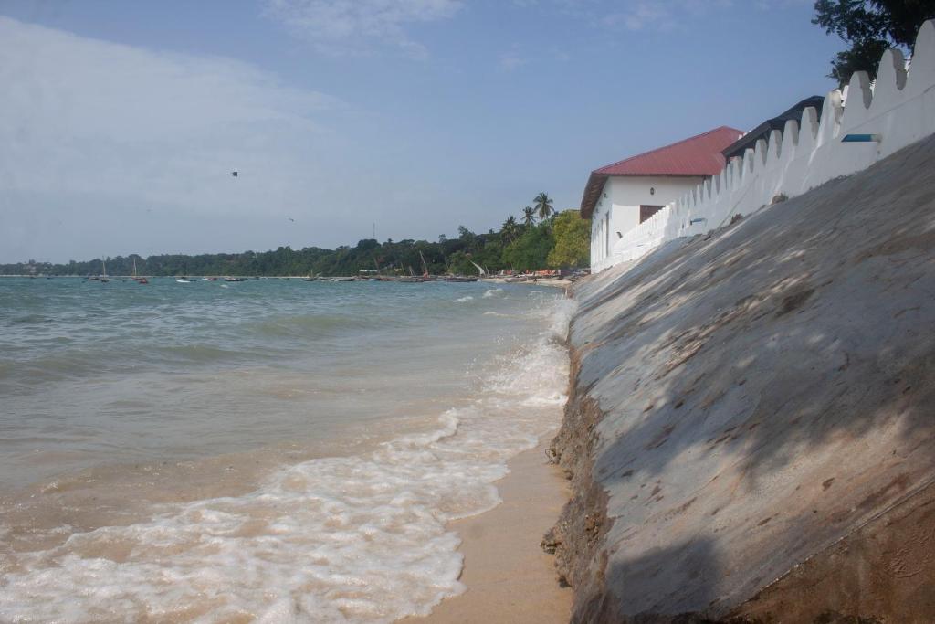 a sandy beach next to the ocean with a white building at Sea View Beach Hotel in Zanzibar City