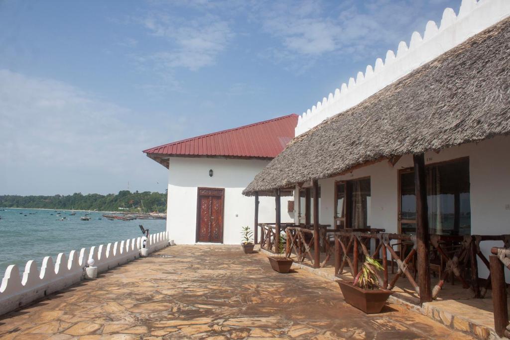 a building with a thatched roof next to the water at Sea View Beach Hotel in Zanzibar City