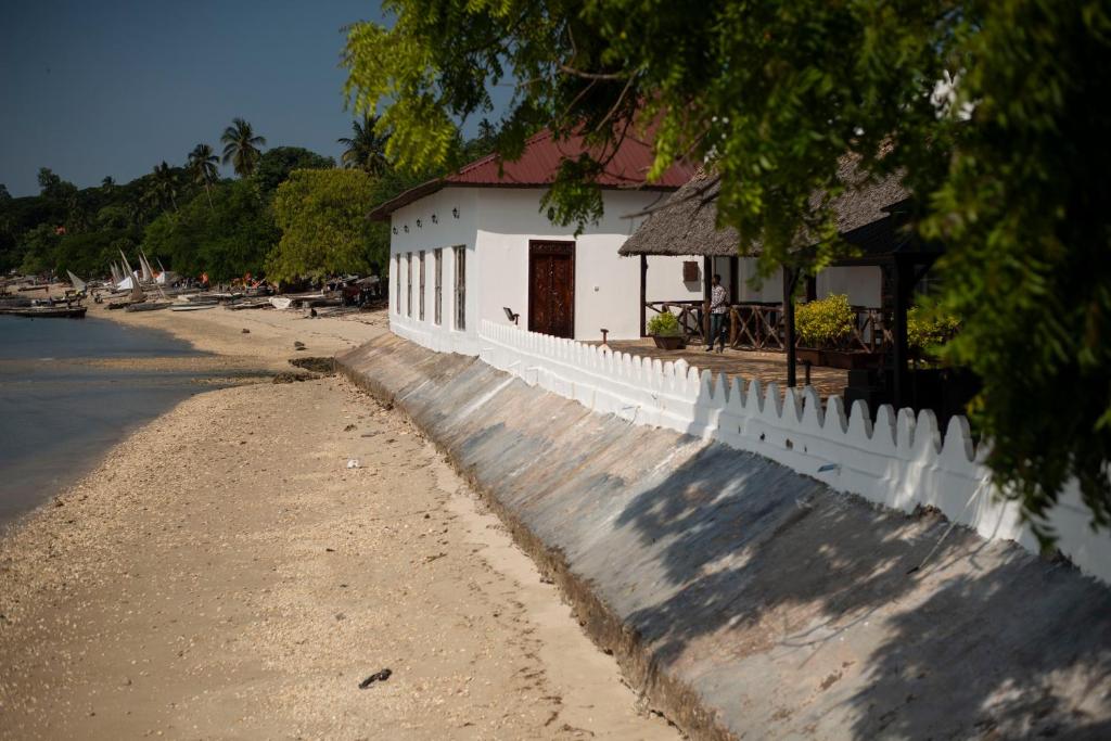 a white building on a beach next to a white fence at Sea View Beach Hotel in Zanzibar City
