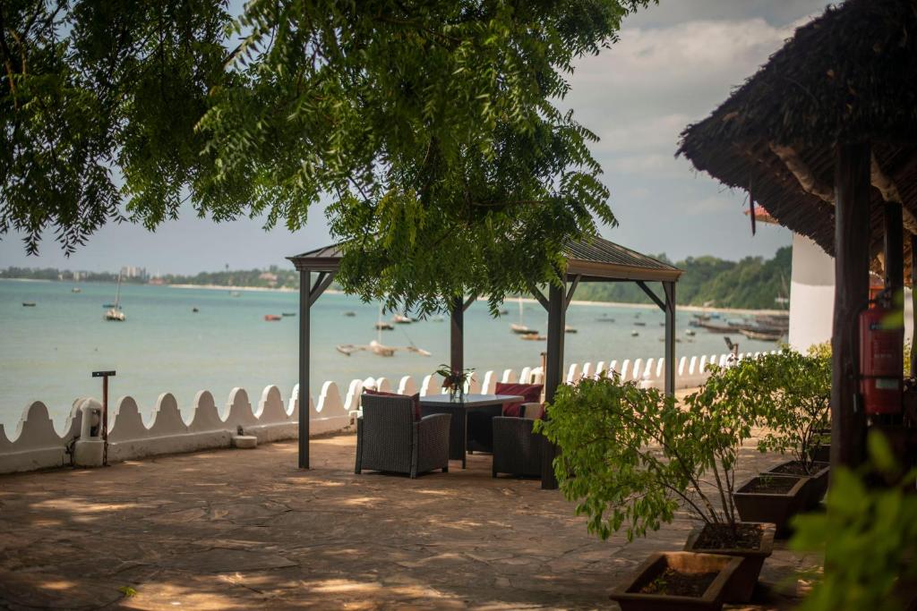 a table and chairs on a beach next to the water at Sea View Beach Hotel in Zanzibar City