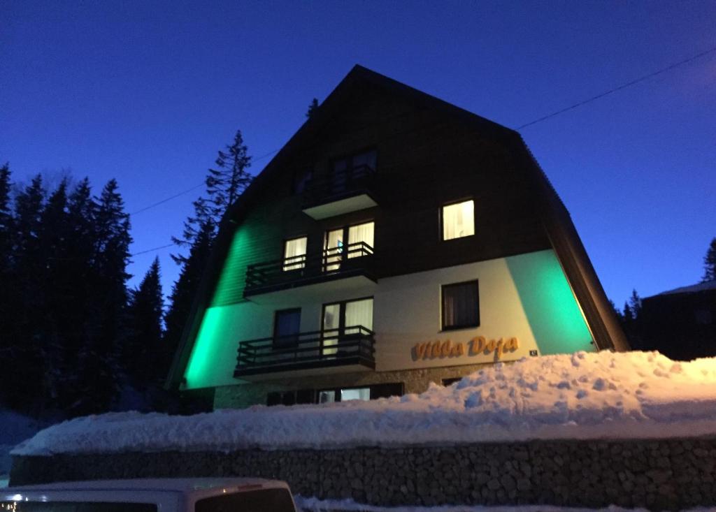 a building with a green light on it in the snow at Apartments Villa Deja in Jahorina
