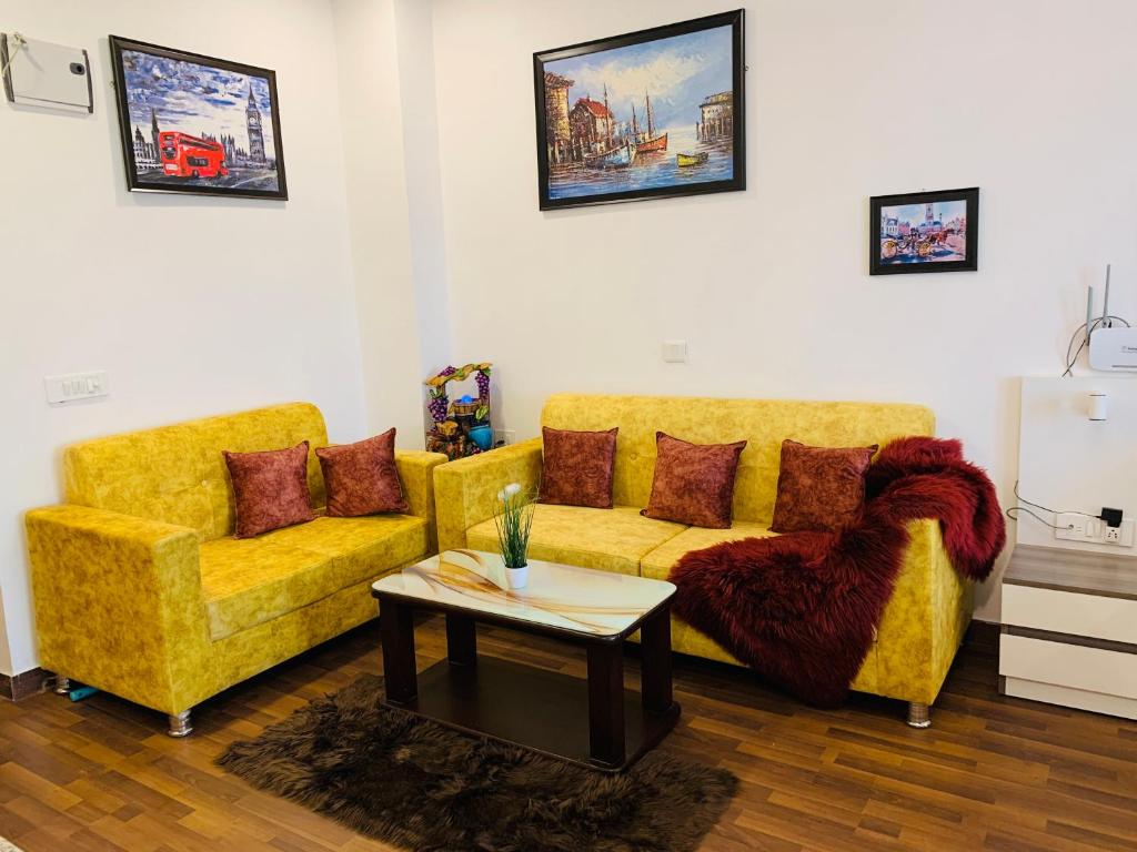 a living room with two yellow couches and a table at The Karma Square near India Expo Mart in Noida