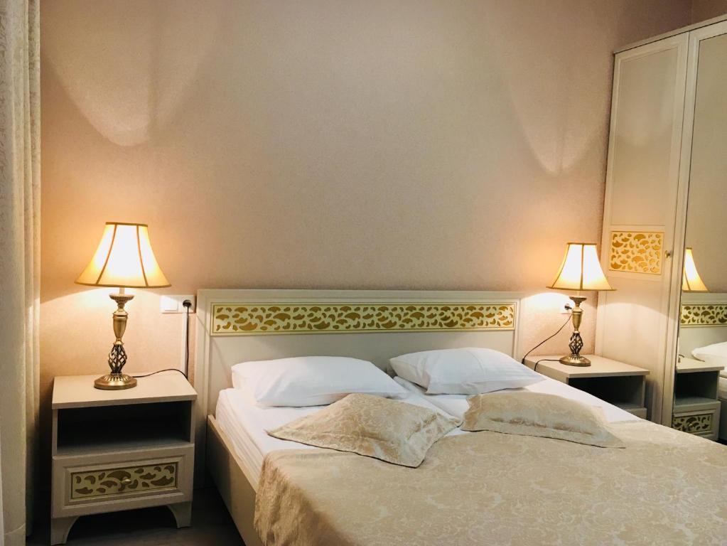 a bedroom with a large bed with two lamps at Guest House near Kolonnady in Kislovodsk
