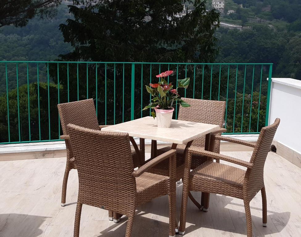 una mesa con sillas y un jarrón con flores en el balcón en Duomo Attic (rooms) en Ravello