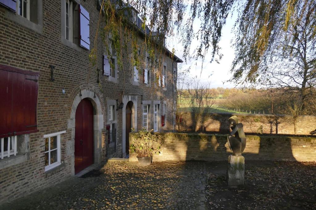a brick building with a statue in front of it at Meschermolen 11 in Eijsden