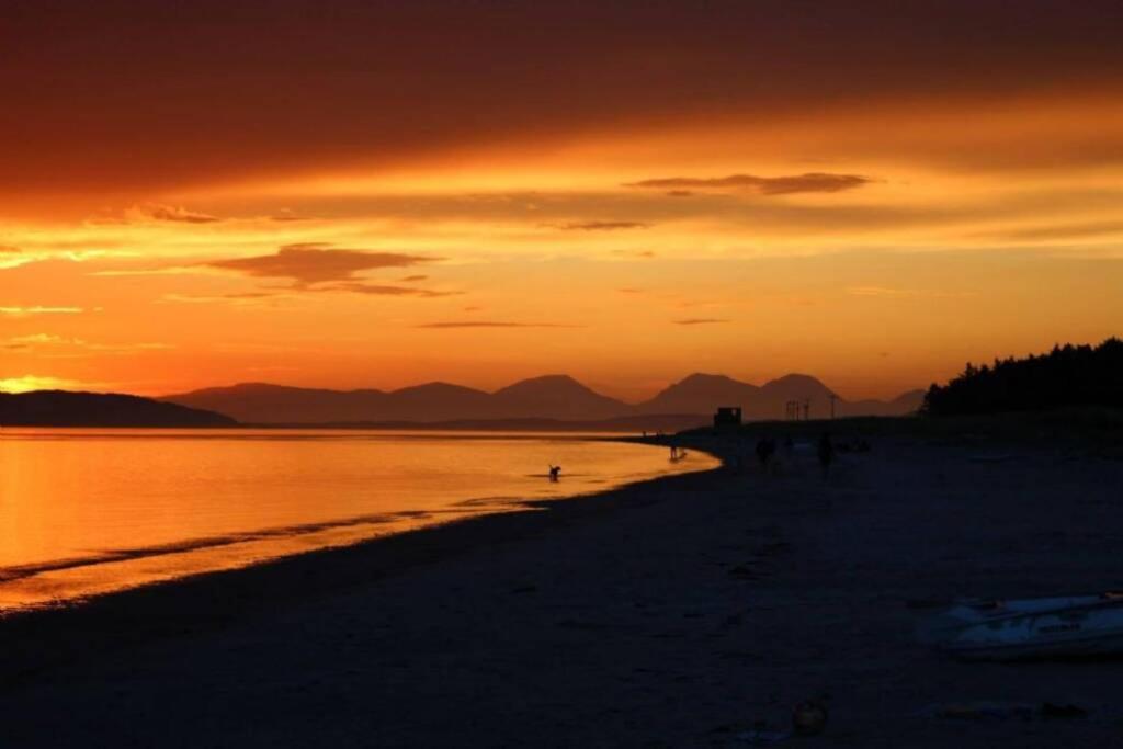 een groep mensen die bij zonsondergang op het strand lopen bij The CaraPod & HotTub - KINTYRE in Tarbert