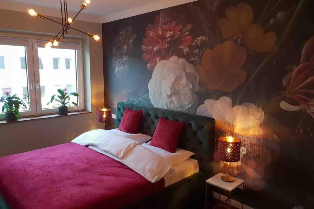 een slaapkamer met een roze bed en een muurschildering van bloemen bij Geschmackvolles Appartement mitten in Düsseldorf in Düsseldorf