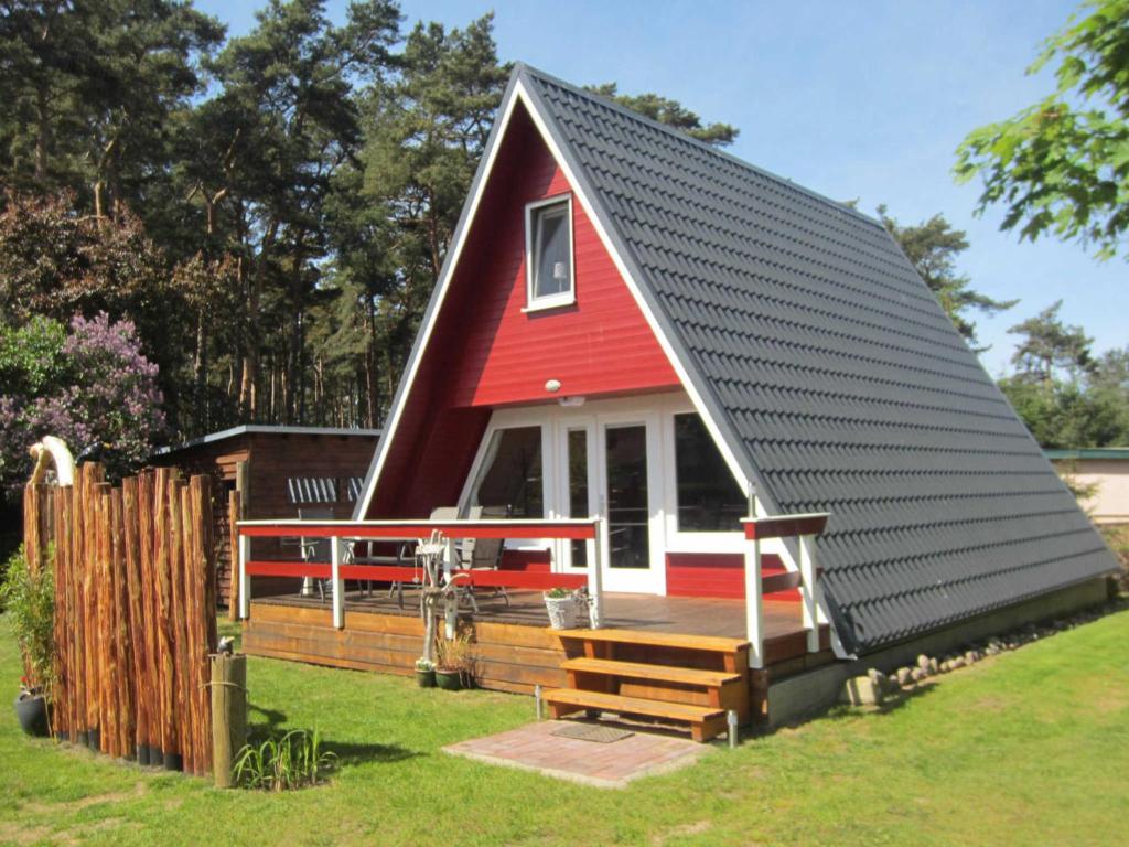 une maison avec un toit rouge et une terrasse dans l'établissement Finnhütte Rabennest, à Freest