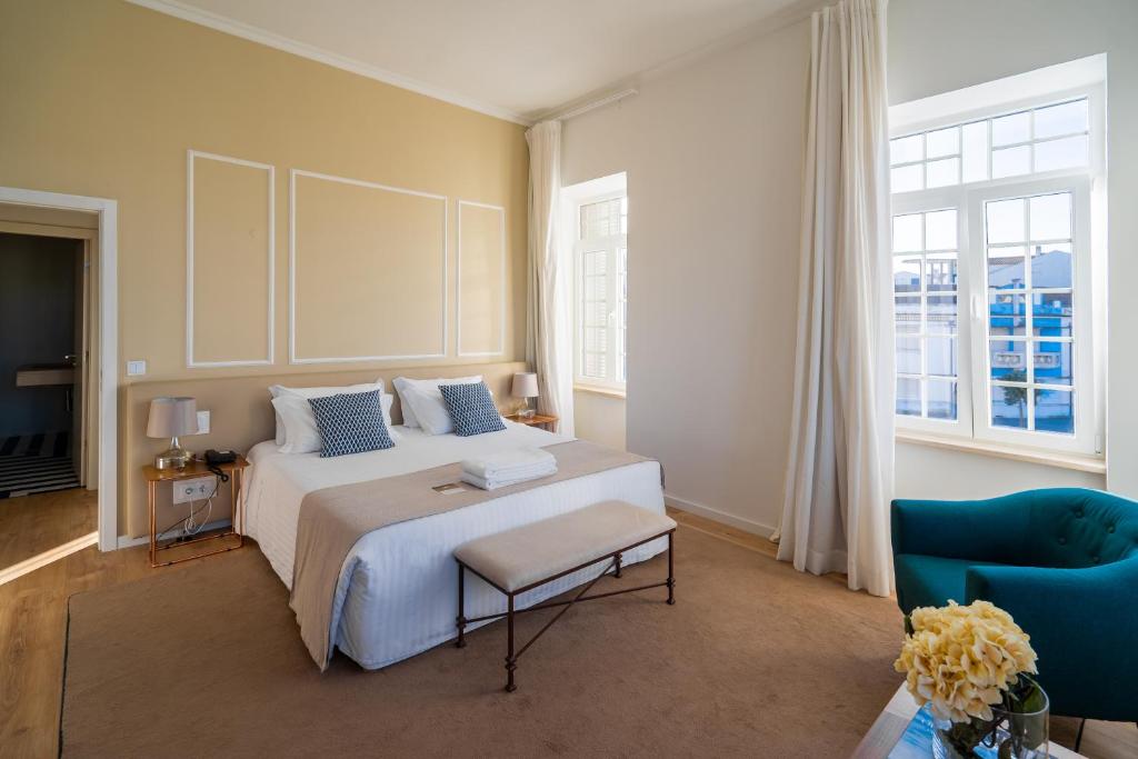 a bedroom with a white bed and a blue chair at Hotel Farol in Praia da Barra