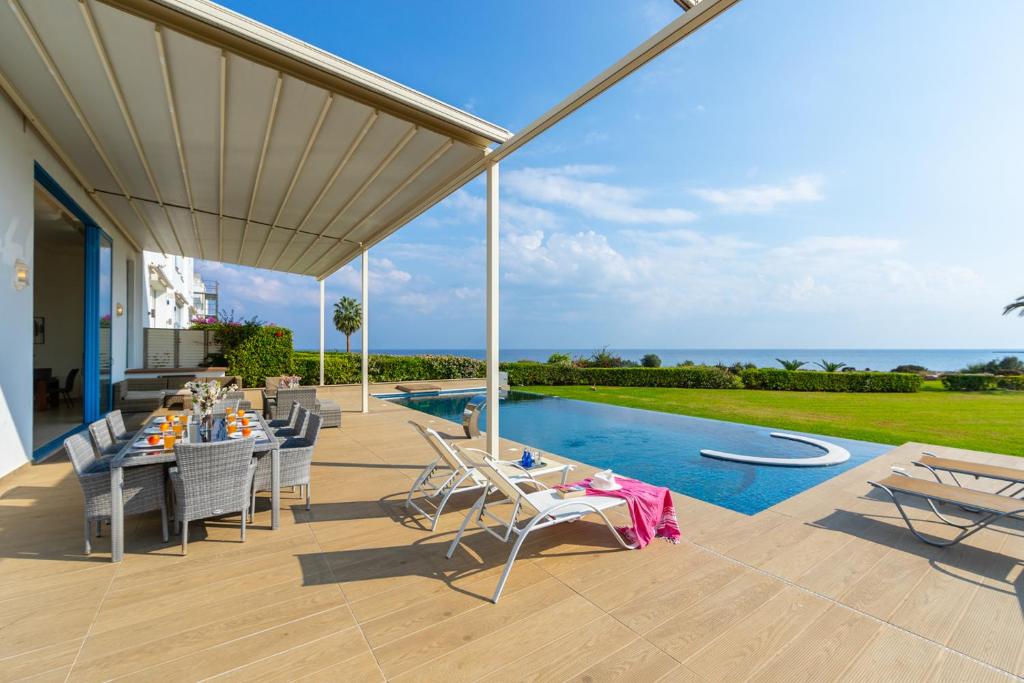 Un patio con mesa y sillas junto a una piscina. en Infinity Villa, en Protaras